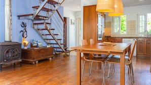 A spacious kitchen with a wooden table and chairs, a built-in oven, and a large window. - Holiday Home 'Aloes' with Shared Pool, Private Terrace and Wi-Fi (Ciutadella de Menorca)