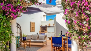 A patio with a wooden table and chairs, a cushioned bench, and potted plants. - Holiday Home 'Aloes' with Shared Pool, Private Terrace and Wi-Fi (Ciutadella de Menorca)