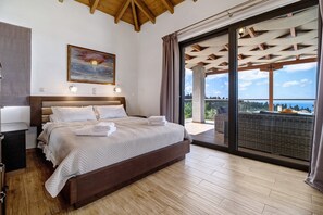 Une chambre avec un grand lit, un tableau et une vue sur l’extérieur, visible à travers une porte vitrée.