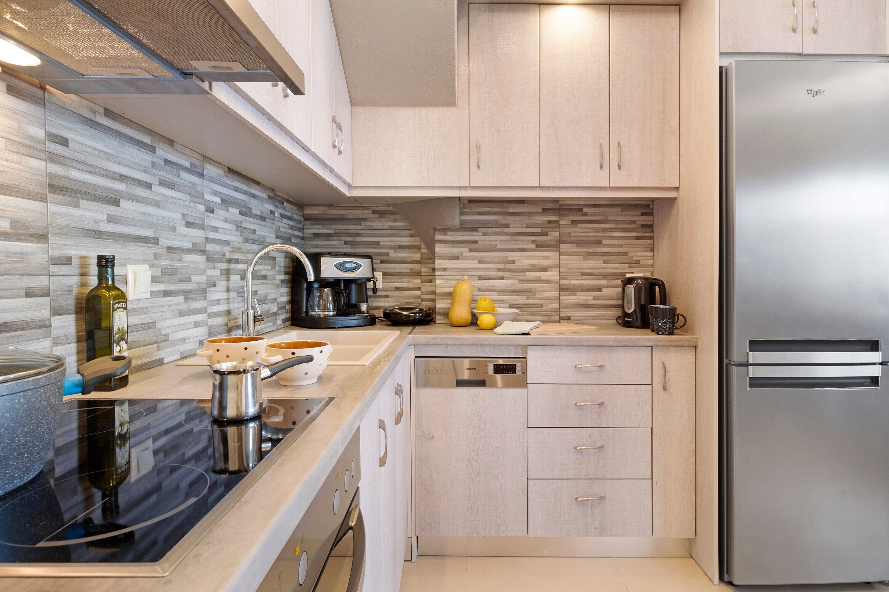 A modern kitchen with a stainless steel refrigerator, a dishwasher, and a coffee maker.