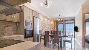A modern kitchen with built-in appliances, a dining area with chairs, and a view of the sea through large windows. - Holiday Apartment "Suite Irida" with Sea View, 2 Terraces & Wi-Fi (Lefkada)