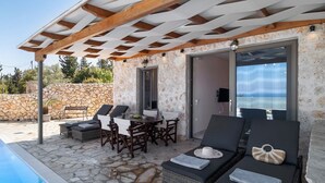 A covered outdoor seating area with stone walls, a pool, and a view of the sea. - Holiday Apartment "Suite Irida" with Sea View, 2 Terraces & Wi-Fi (Lefkada)