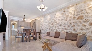 A modern living room with a stone wall, a glass coffee table, and a sofa. - Holiday Apartment "Suite Irida" with Sea View, 2 Terraces & Wi-Fi (Lefkada)