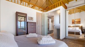 Un dormitorio con una cama grande, un armario, un espejo y una puerta corredera que da a un baño.