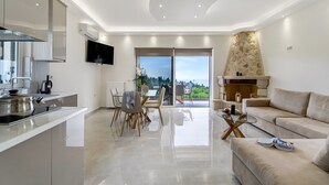 Una cocina moderna con comedor, una sala de estar con sofá y una chimenea de piedra.