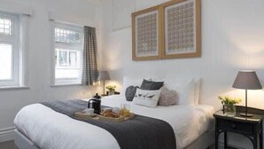A neatly arranged bedroom with a large bed, bedside tables, and a window with curtains. - The Lookout - Beautiful sea views (Filey)