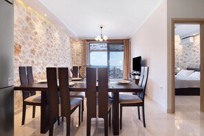 A dining area with a table and chairs, a television, and a view of the city through a large window.