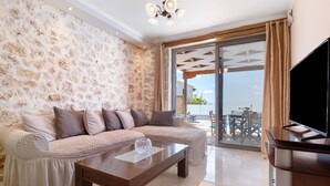 Ein Wohnzimmer mit Steinwand, einer Couch, einem Couchtisch und einem Fernseher.