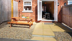 A brick house with a wooden bench and a table outside, a window, and a door leading to a patio area. - Sea Dreams, Sleeps 5, great central location (Filey)