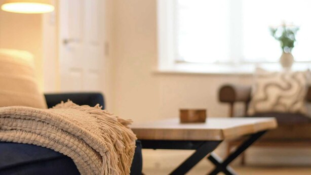 A cozy living room with a sofa, a coffee table, and a lamp. - Sea Dreams, Sleeps 5, great central location (Filey)