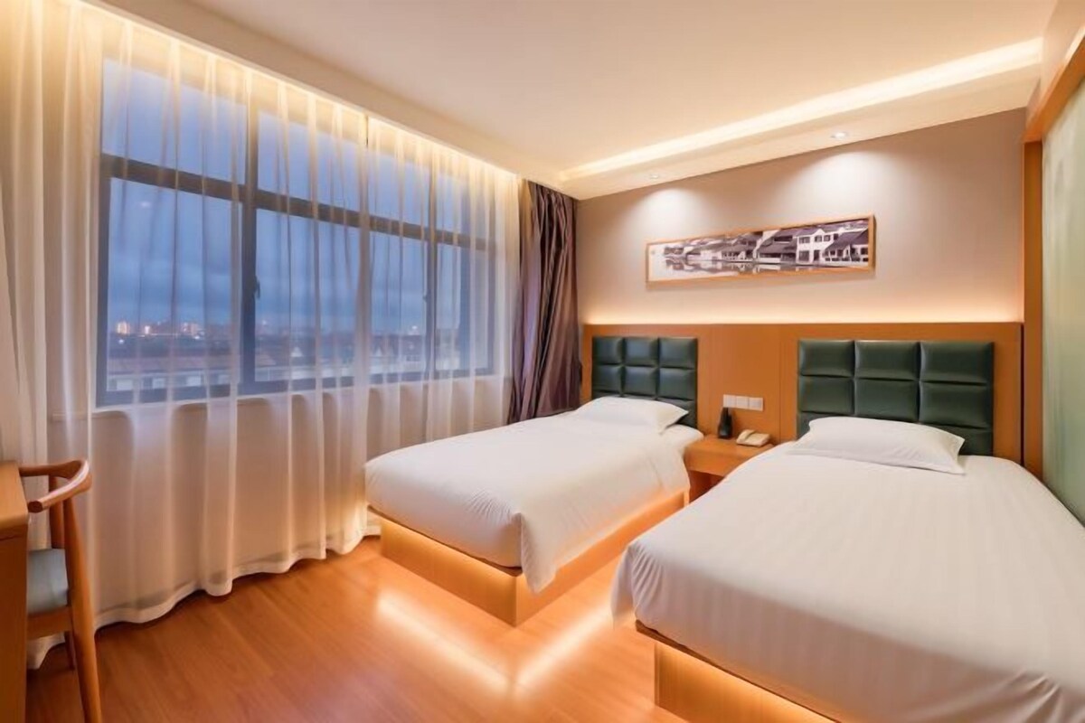 Habitación de hotel con dos camas, un escritorio y vistas a la ciudad.