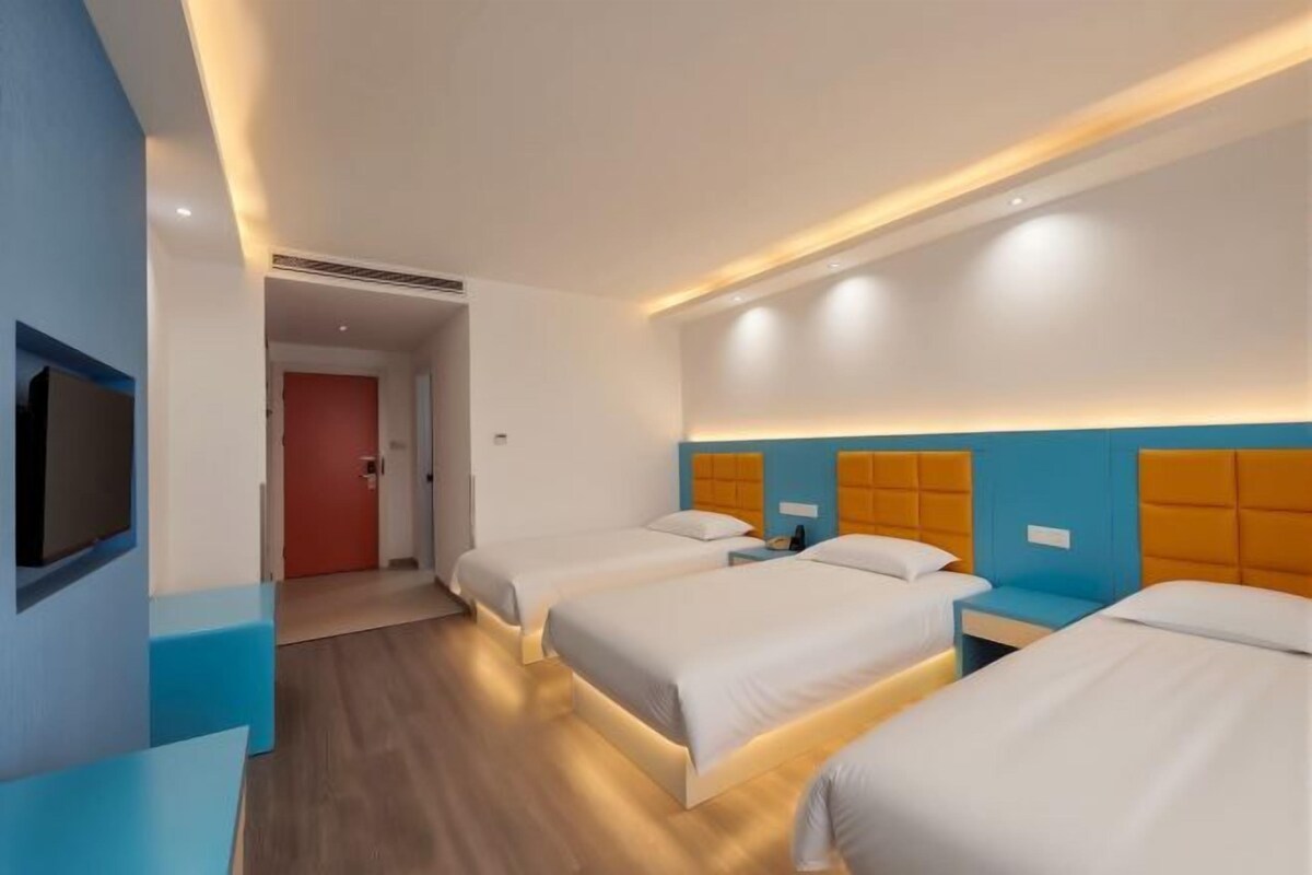 Una habitación de hotel con tres camas, un televisor y un escritorio.