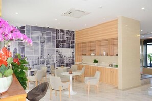 A modern kitchen with wooden cabinets, a dining area with white chairs, and a cityscape mural on the wall. - Hongyi Boutique Hotel (Shanghai)