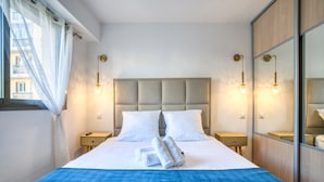 Una habitación de hotel con una cama grande, dos mesitas de noche, un espejo y una ventana con cortinas.