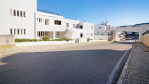 A street with white buildings, a clear sky, and a bridge in the distance.