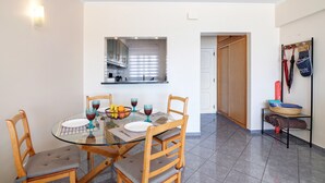 A dining area with a glass table, wooden chairs, and a bowl of fruit.