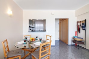 A dining area with a glass table, wooden chairs, and a bowl of fruit.