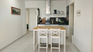 Eine Küche mit einem Holztisch, weißen Stühlen, einer schwarzen Arbeitsplatte und einer Edelstahl-Dunstabzugshaube.