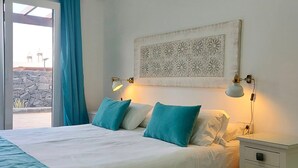 Ein Schlafzimmer mit Bett, Nachttisch, Wand-Klimaanlage, Fenster mit Vorhängen und einem Wanddekor.