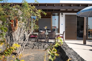 An outdoor patio with a table and chairs, a stone wall, and a wooden pergola.