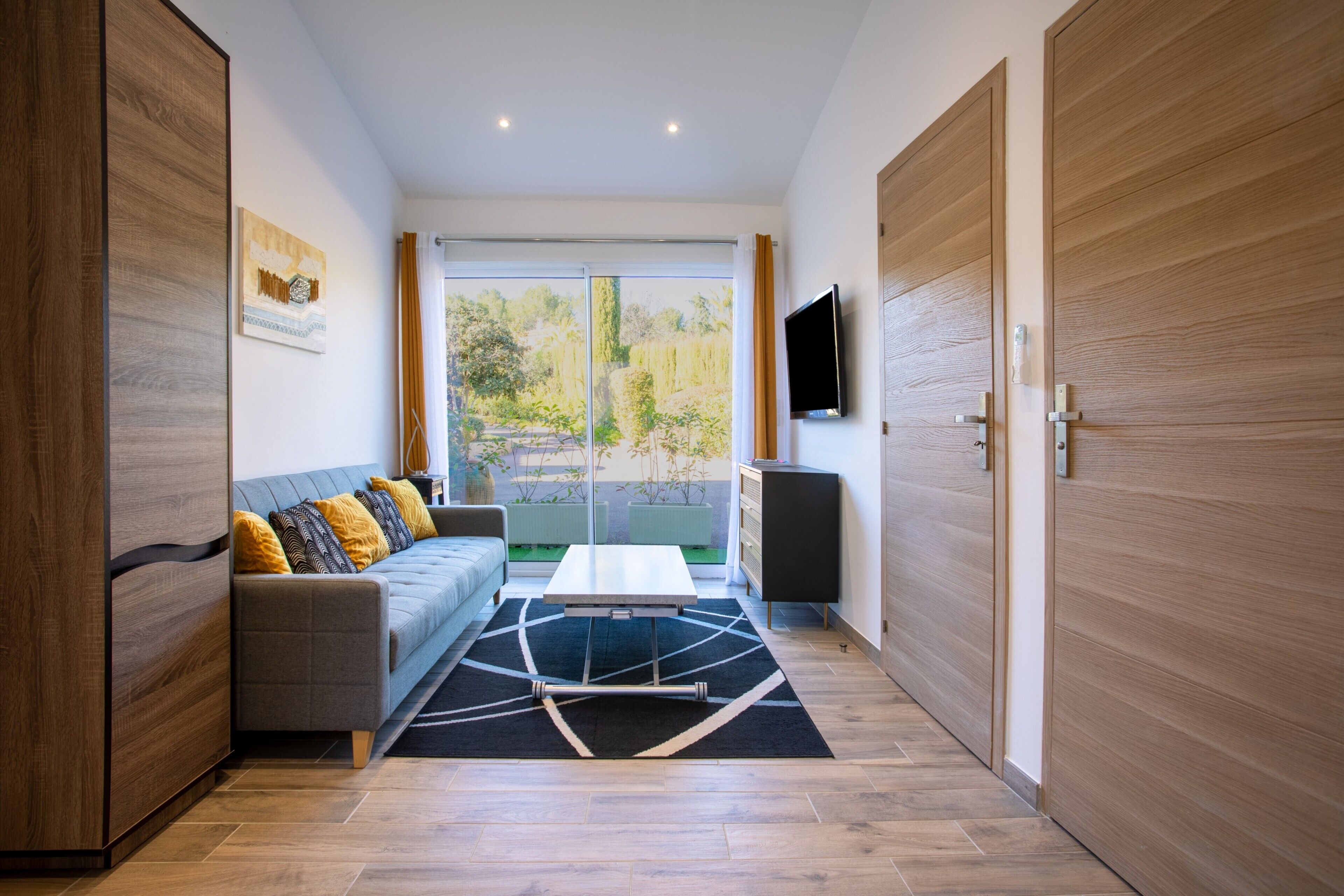 A modern living room with a sofa, coffee table, and a TV mounted on the wall.