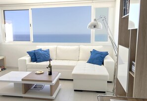 A modern living room with a white sofa, blue cushions, a coffee table, and a floor lamp.