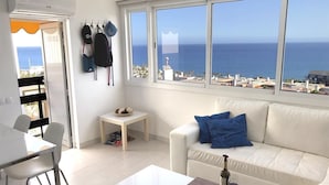 Ein modernes Wohnzimmer mit einem weißen Sofa, einem kleinen Tisch und einem Essbereich.