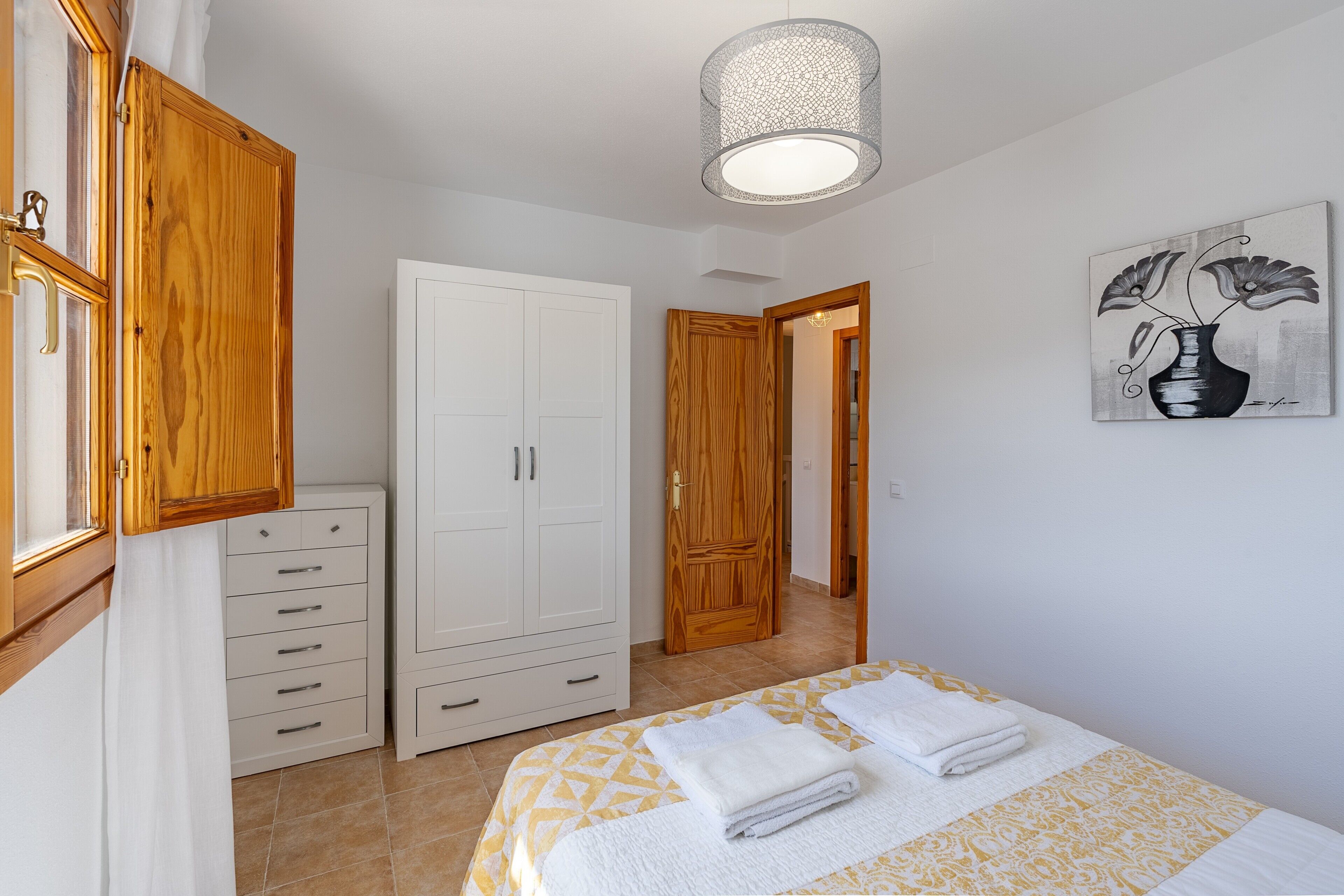 A bedroom with a bed, a wardrobe, a door, and a painting on the wall.