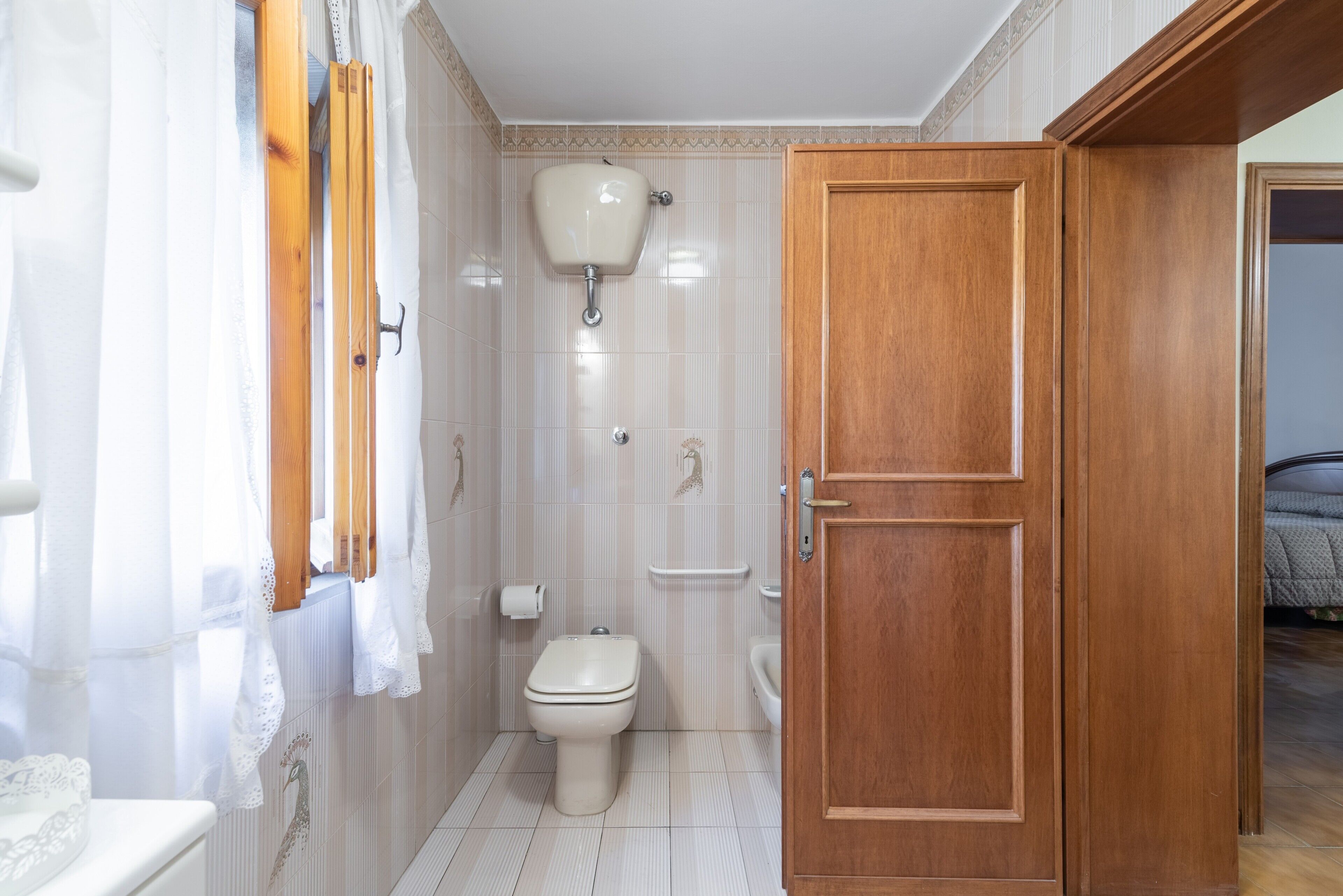 Une salle de bain avec des toilettes, un rideau de douche et une porte en bois.