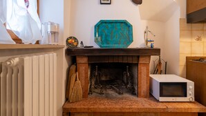 Una cocina con chimenea, microondas y una rústica repisa de madera.