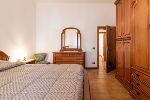 A bedroom with a bed, dresser, mirror, and a door leading to another room. - Holiday Home "Le Balze" with Mountain View, Private Garden & Wi-Fi (Castelfranco di Sopra)