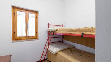 Une chambre avec un lit superposé, une échelle en bois, une fenêtre avec des rideaux et une petite table en bois.