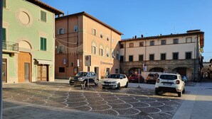 Una calle con coches estacionados y edificios con ventanas y balcones de arco.