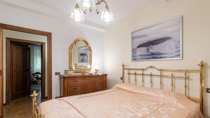 Un dormitorio con cama, cómoda, espejo e imagen de una ballena colgada en la pared.