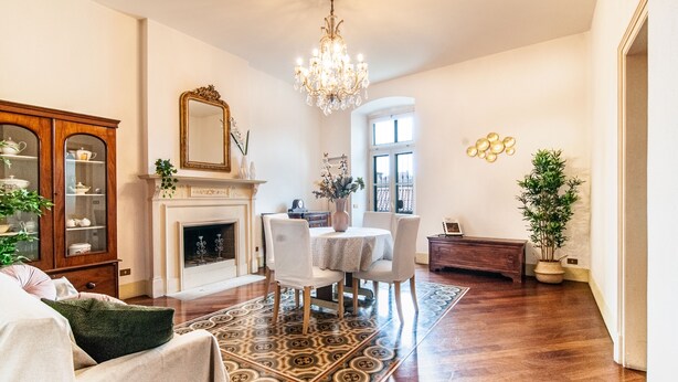 Un vaste salon doté d’une cheminée, d’un lustre et d’un coin repas.