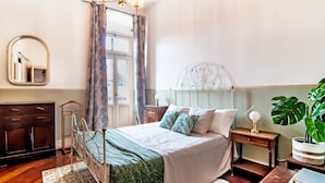 Une chambre à coucher avec un lit, une table de chevet, un miroir, une armoire et une plante en pot.