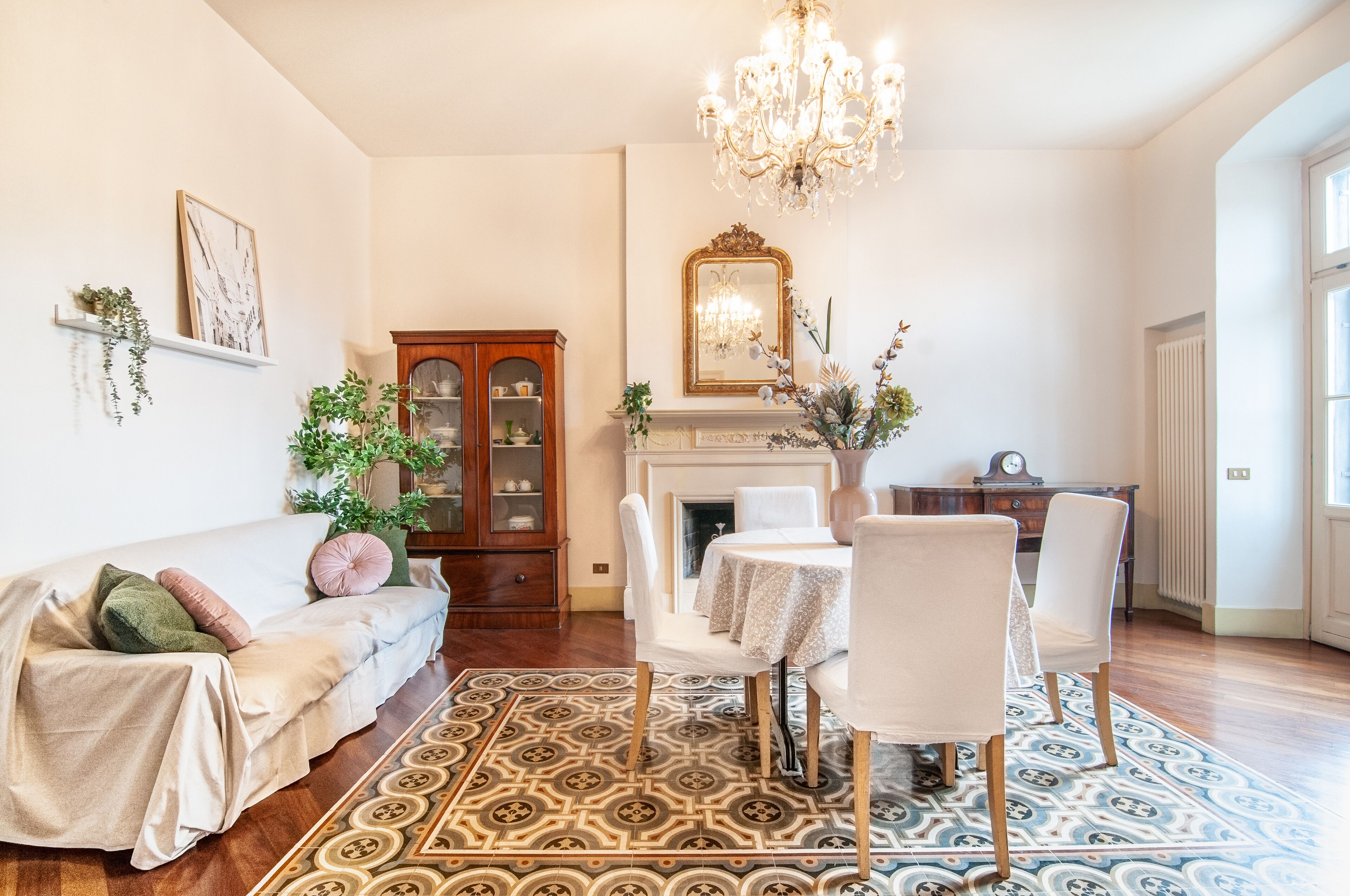 A living room with a sofa, chairs, a fireplace, a chandelier, and a patterned rug.