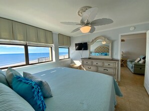 A bedroom with a large bed, a ceiling fan, a dresser, a TV, and a view of the ocean. - Gorgeous and Gulf Front! Pool! (Gulf Shores)