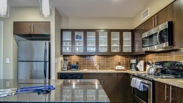 Eine moderne Küche mit einem Edelstahl-Kühlschrank, einer Mikrowelle, einem Backofen und einem Geschirrspüler.