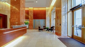 Eine Hotelhalle mit Empfangstresen, Sitzgelegenheiten und großen Fenstern.