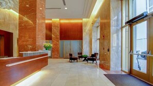 Vestíbulo de hotel con recepción, zona de estar y grandes ventanales.
