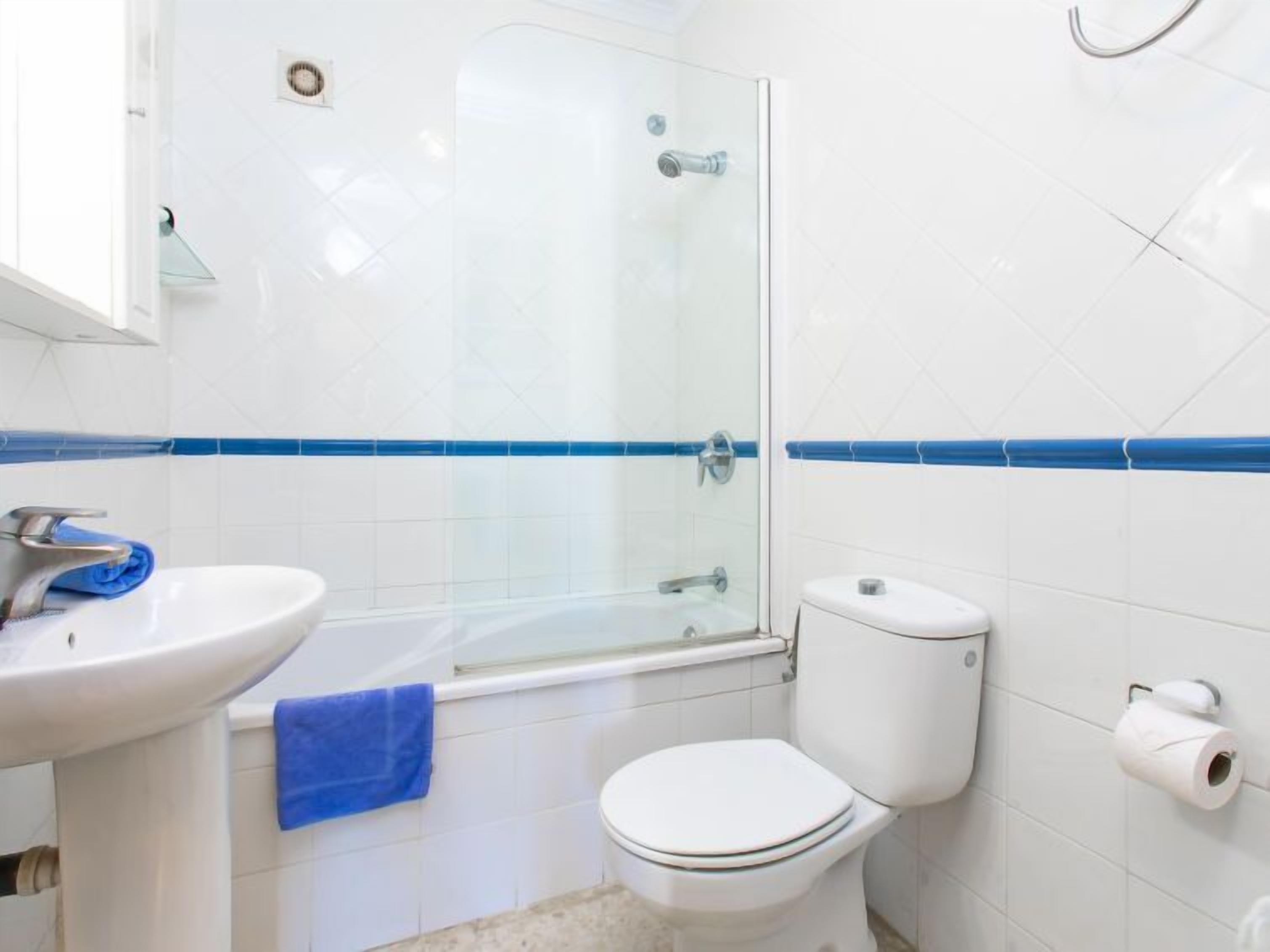 A bathroom with a glass shower enclosure, a white sink, and a toilet.