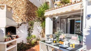 A patio with a stone wall, a grill, and outdoor seating.