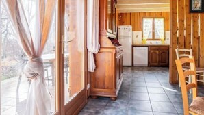 Un intérieur en bois comprenant un espace cuisine, avec des placards, un réfrigérateur et une table à manger avec des chaises.