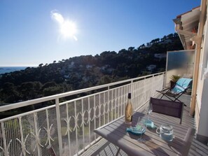 A balcony with a table, two chairs, a bottle, and glasses.