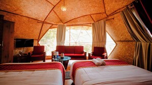 A cozy, tent-like room with two beds, a sofa, and a television. - Tapasya Home (Virajpet)