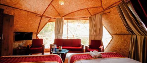A cozy, tent-like room with two beds, a sofa, and a television.