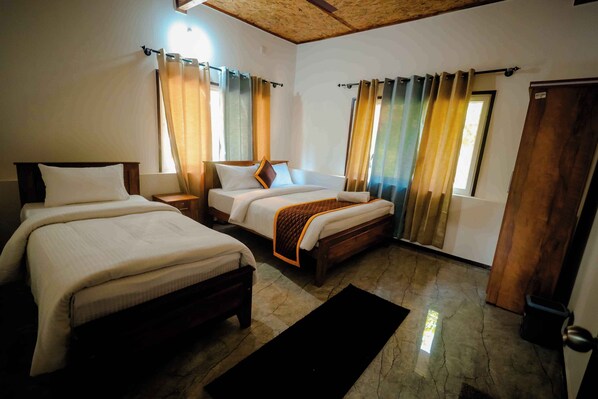 A hotel room with two beds, a wooden ceiling, and a large window with curtains.