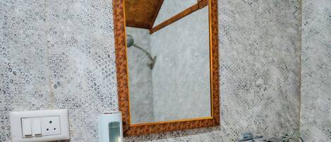 A bathroom with a white sink, a mirror with a wooden frame, a soap dispenser, and a towel rack.