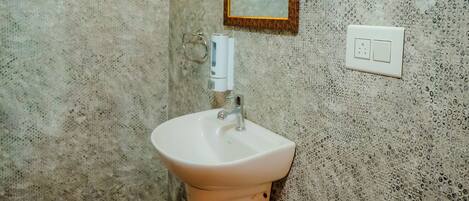 A bathroom with a textured wall, a white sink, a mirror, and a window with a wooden frame.